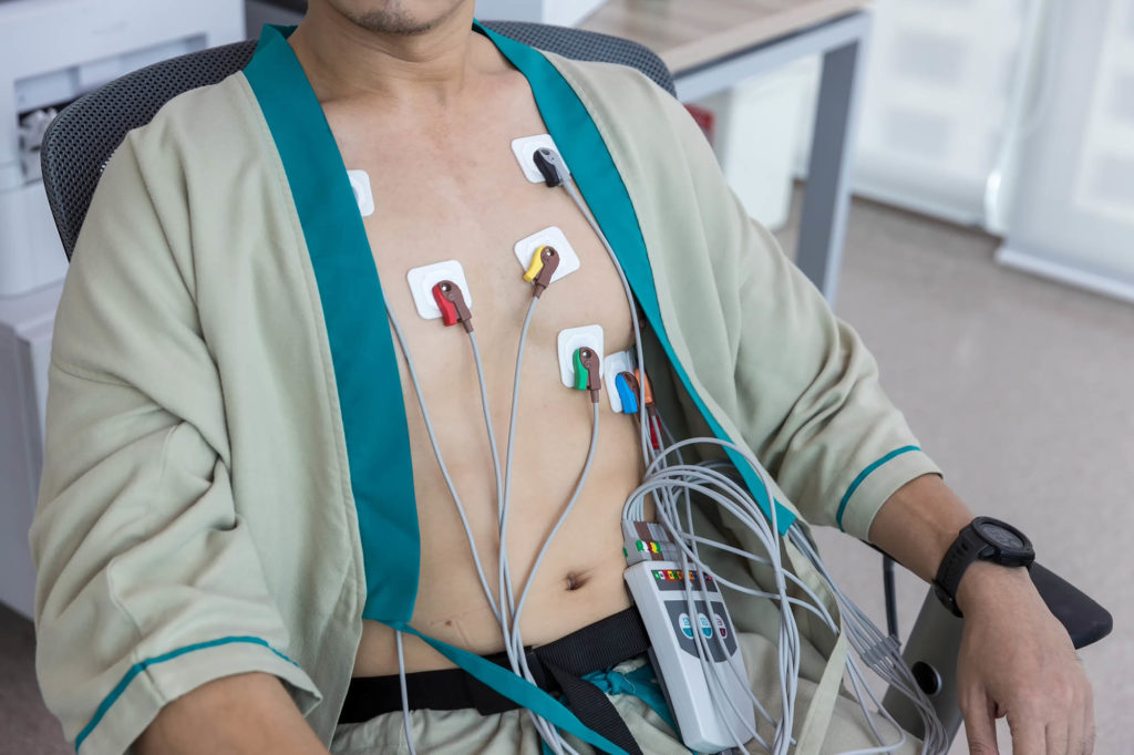 Heart electrocardiogram or monitoring using Holter for young patient. Male athlete does a cardiac stress test. wearing Holter monitor device for daily monitoring of an electrocardiogram.